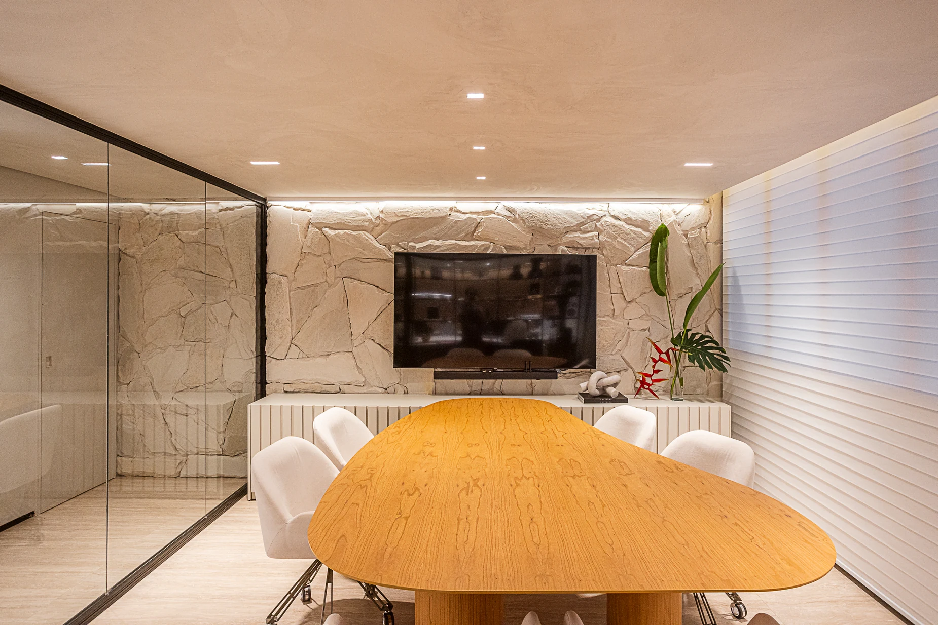 Sala de reunião com mesa de madeira e parede de pedra